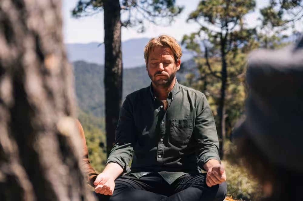 Person meditating while leaning against a tree trunk